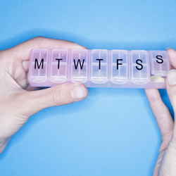 Hands holding weekly pill container