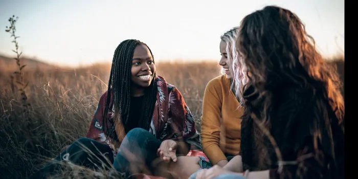 Three women sitting in a field talking